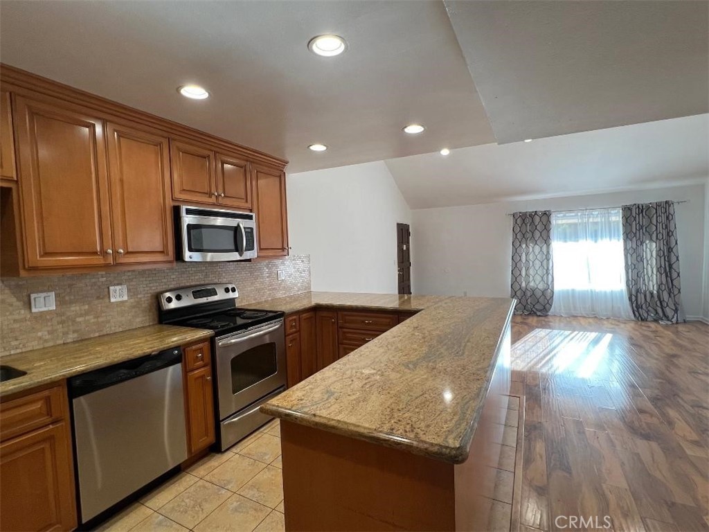 a kitchen with stainless steel appliances granite countertop wooden cabinets a stove a sink and dishwasher