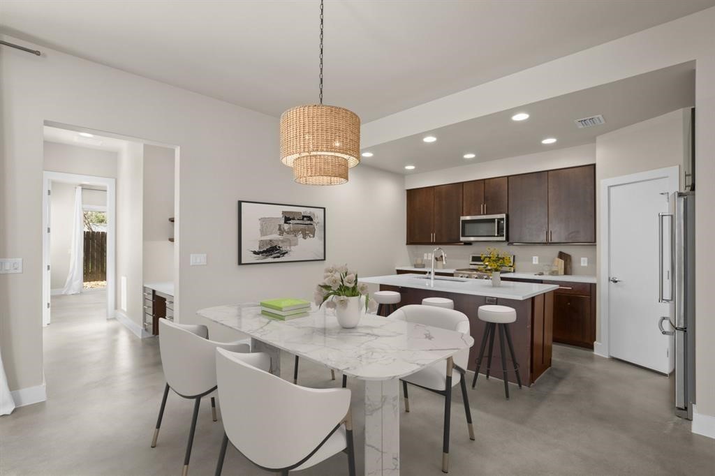 a view of a dining room with furniture a kitchen and chandelier