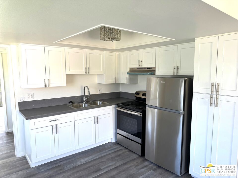 a kitchen with granite countertop a refrigerator sink and cabinets