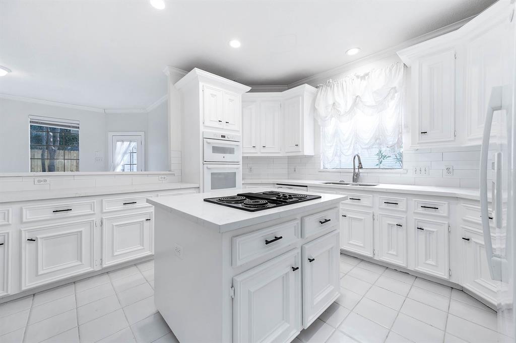 a kitchen with white cabinets appliances and a window