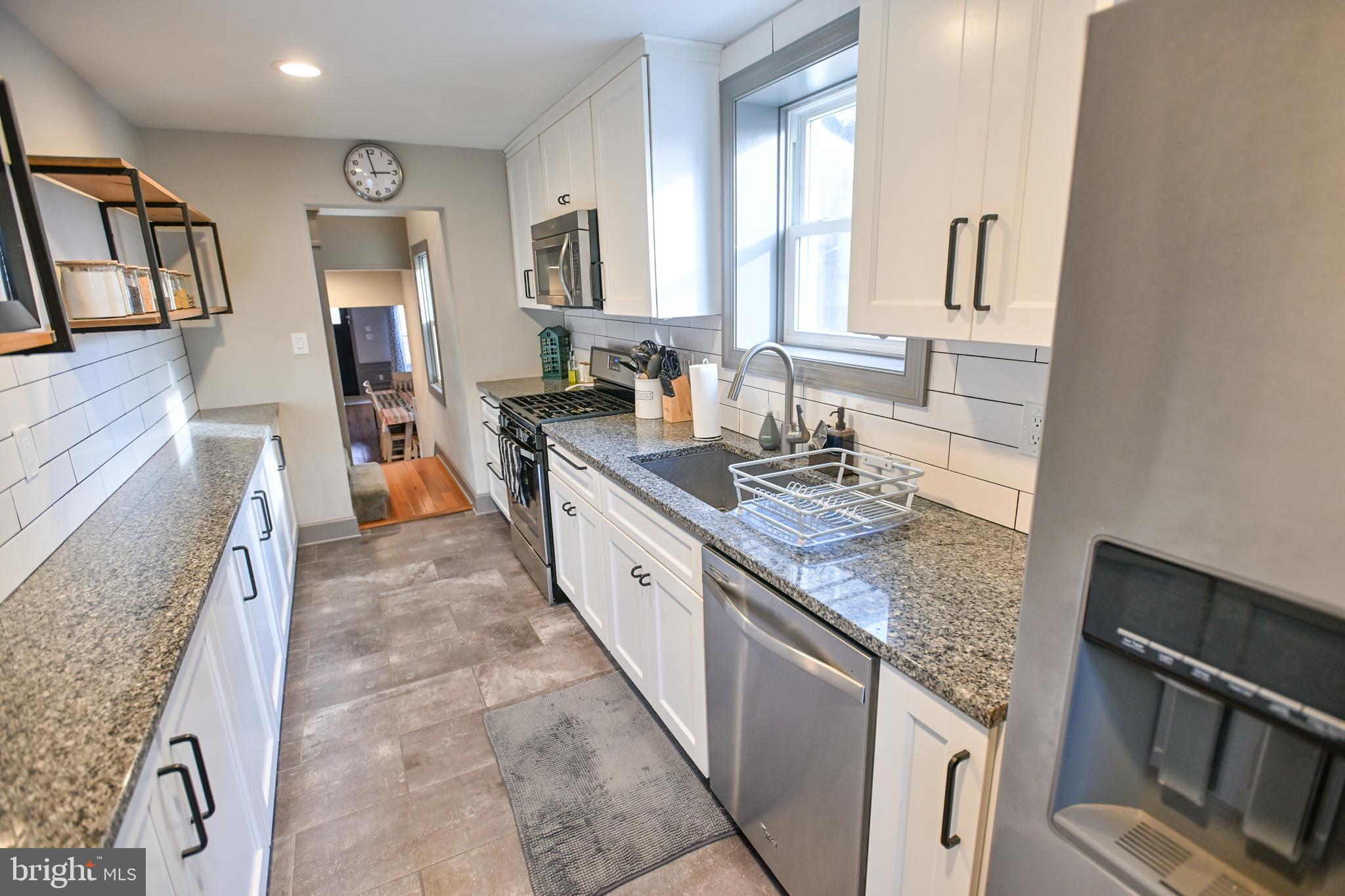 a large kitchen with granite countertop a sink stove and cabinets