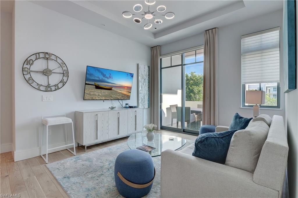 a living room with furniture a chandelier and a flat screen tv