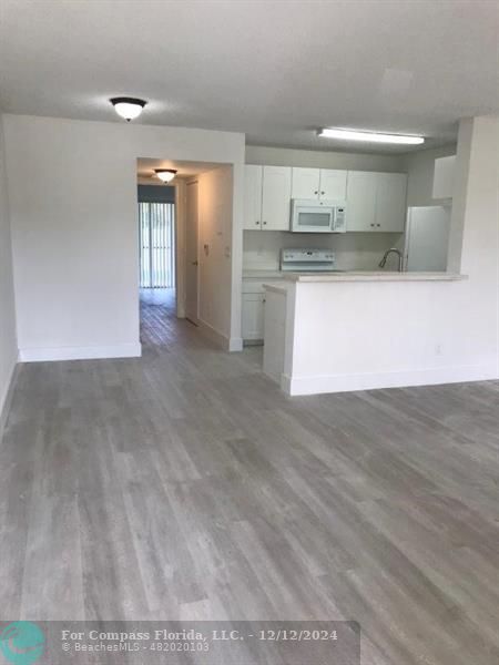 a view of kitchen with kitchen island a sink wooden floor and stainless steel appliances