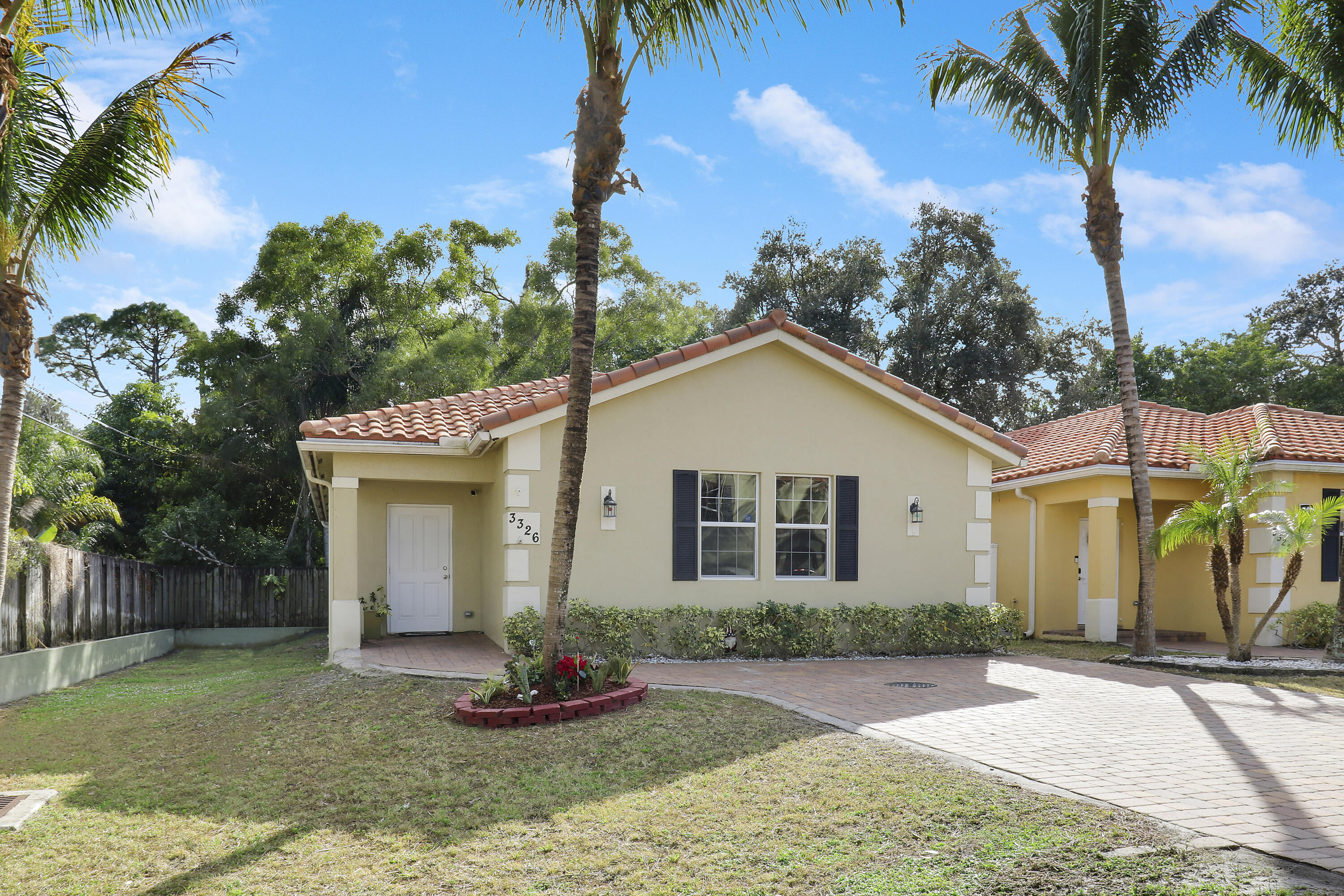 a view of a white house with a yard and palm trees