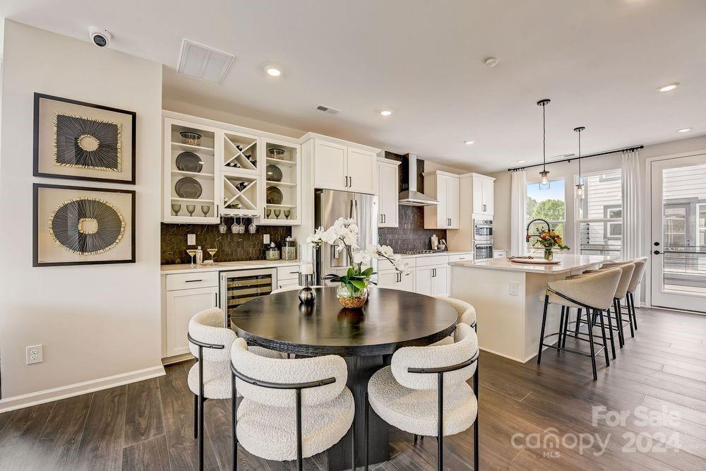 a kitchen with stainless steel appliances granite countertop a dining table chairs and white cabinets