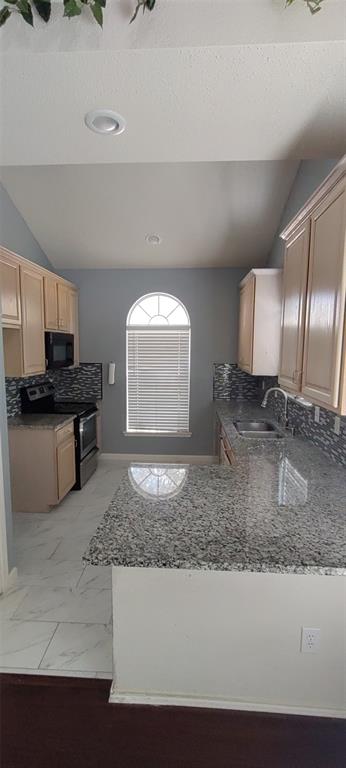 a kitchen with granite countertop a sink a stove and a refrigerator