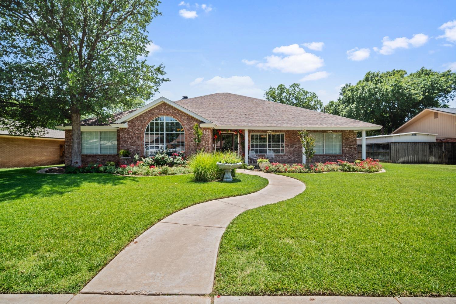 a view of a house with a big yard plants and large trees