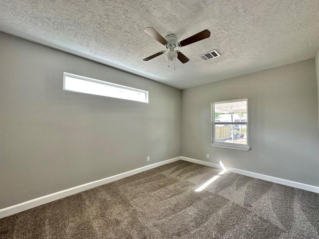 an empty room with a window and ceiling fan