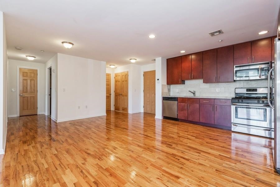 a view of kitchen with kitchen island granite countertop wooden cabinets and stainless steel appliances