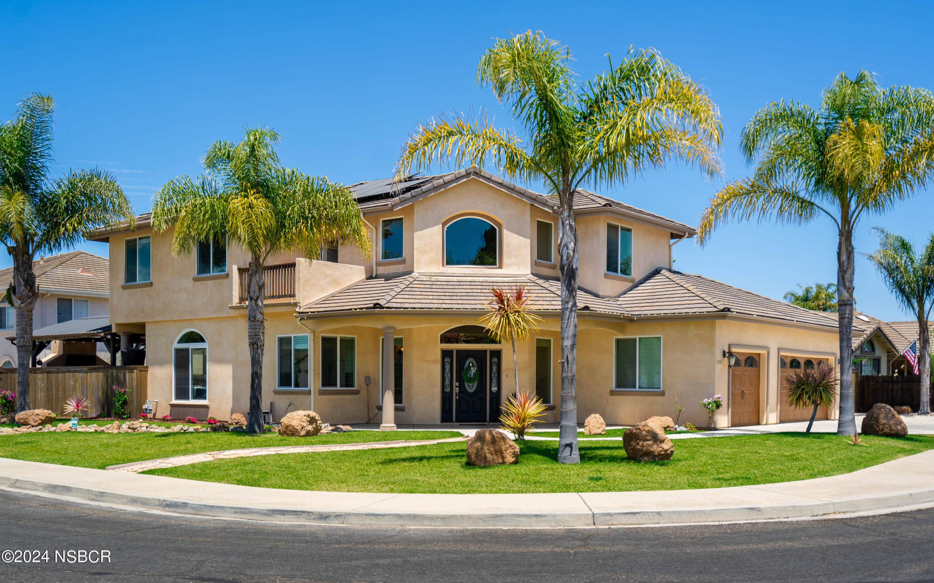 a front view of a house with a garden and trees