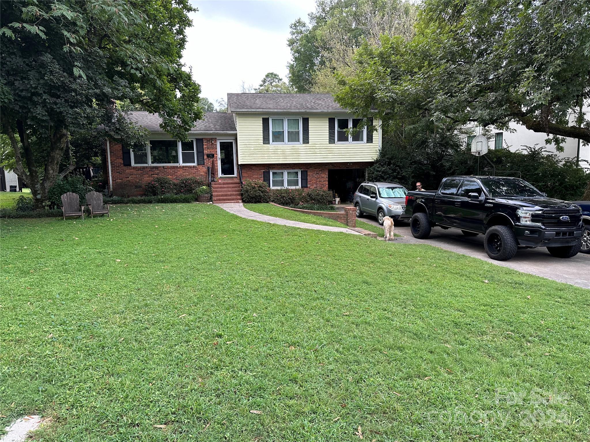 a view of house with a big yard and large trees