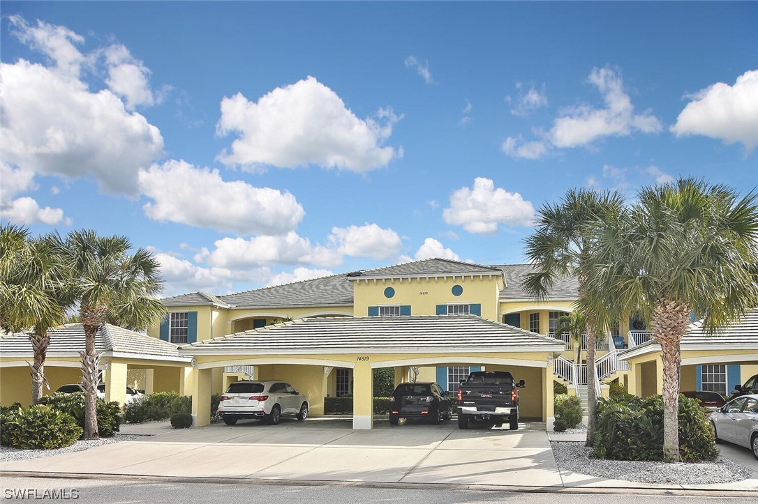 a front view of a building with lot of cars and trees