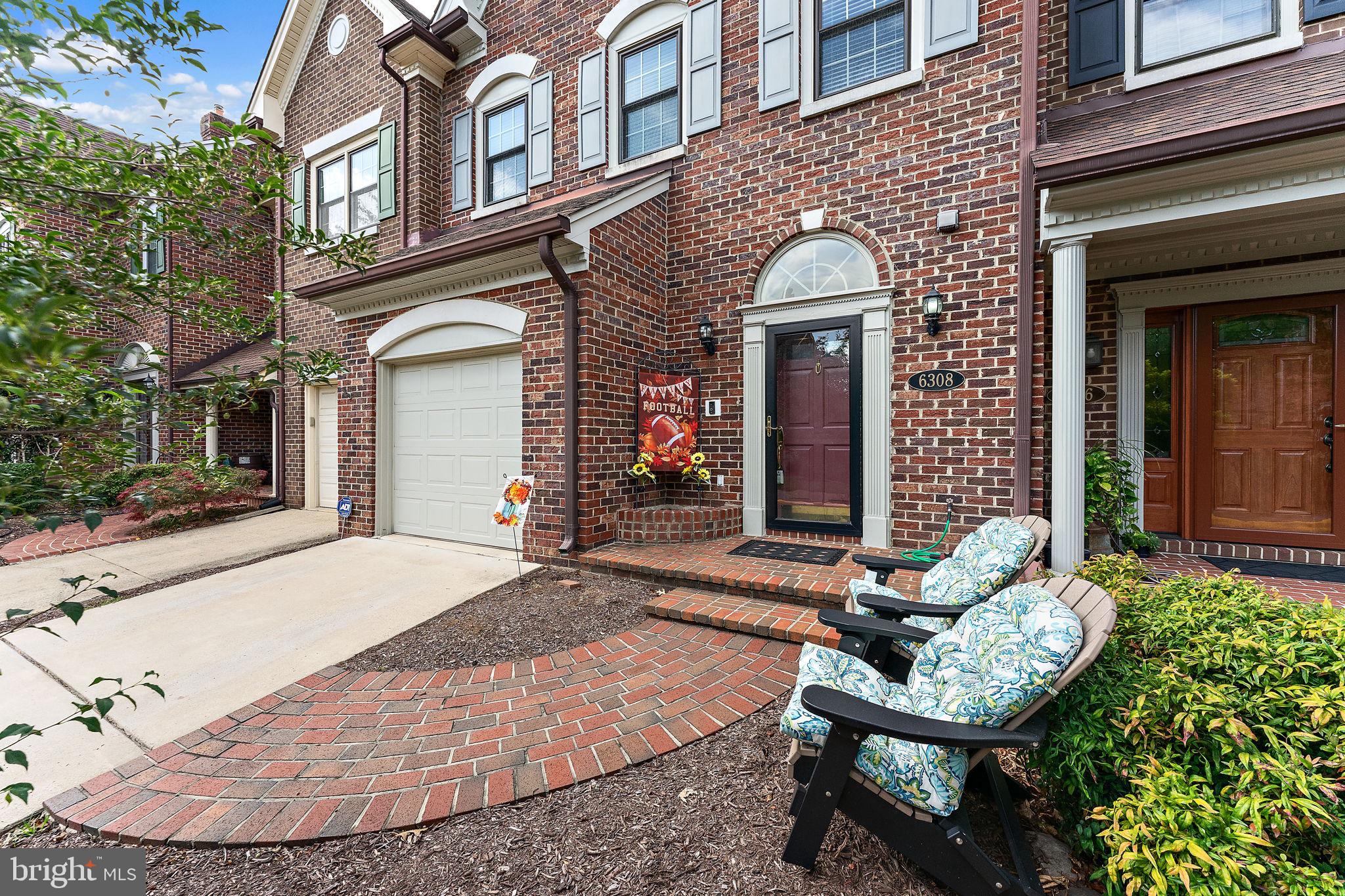 a view of a brick house with potted plants and a bench