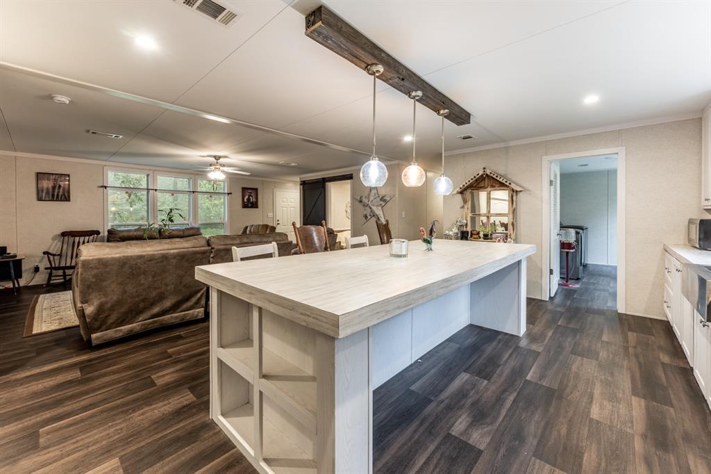 a large white kitchen with a stove a sink dishwasher and a refrigerator with wooden floor