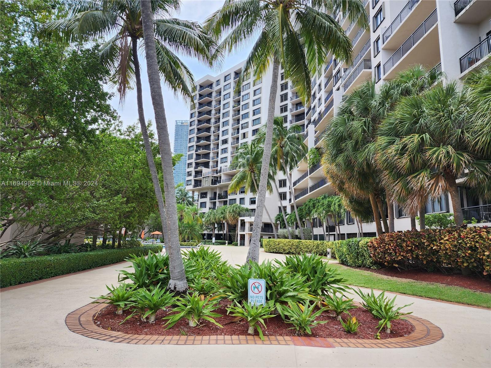 a front view of a multi story residential apartment building with yard and green space