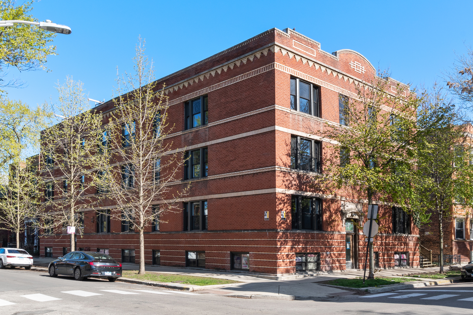 a front view of a building with lot of cars and trees