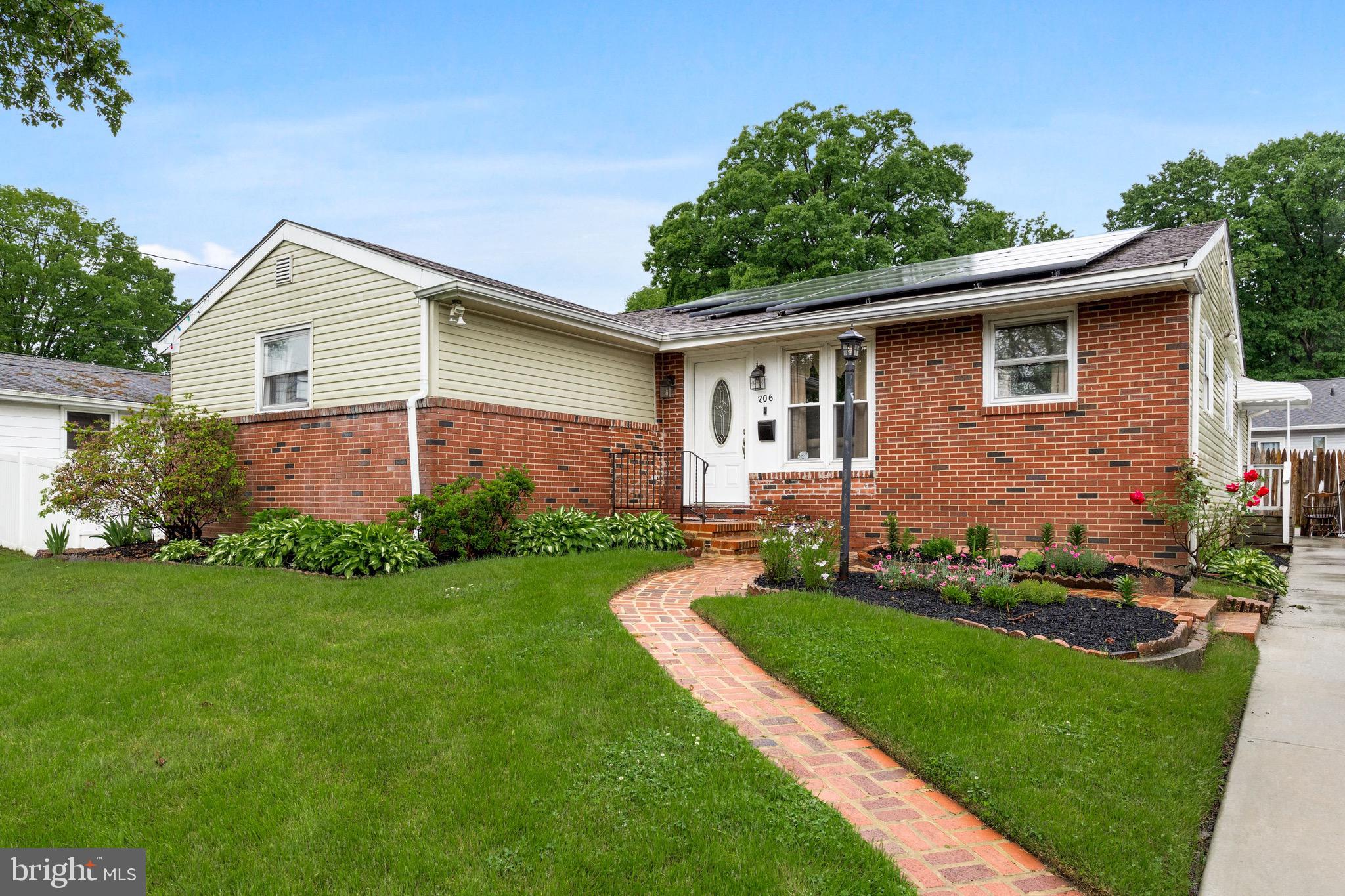 a view of a house with a yard plants and large tree