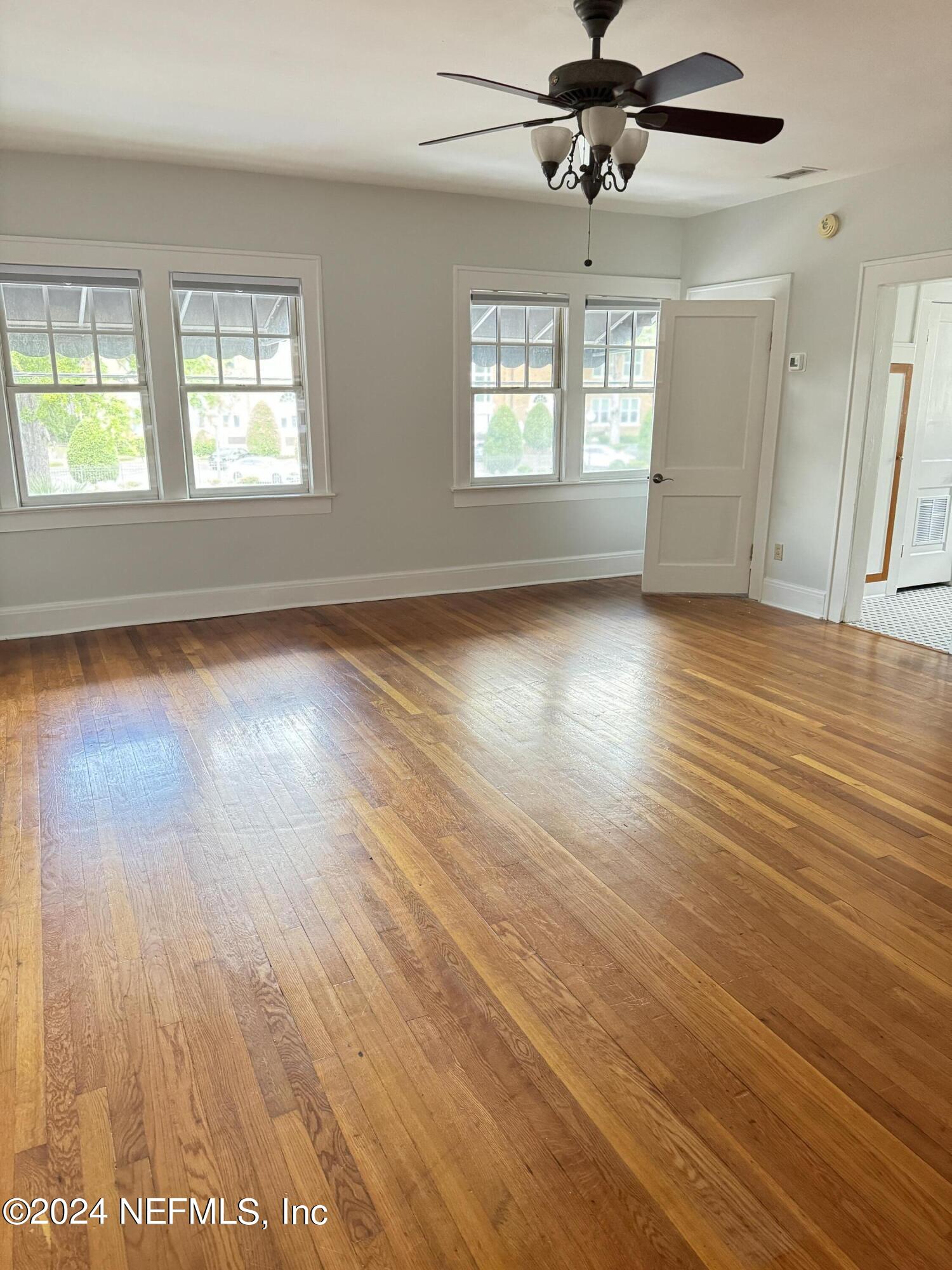 an empty room with wooden floor and windows