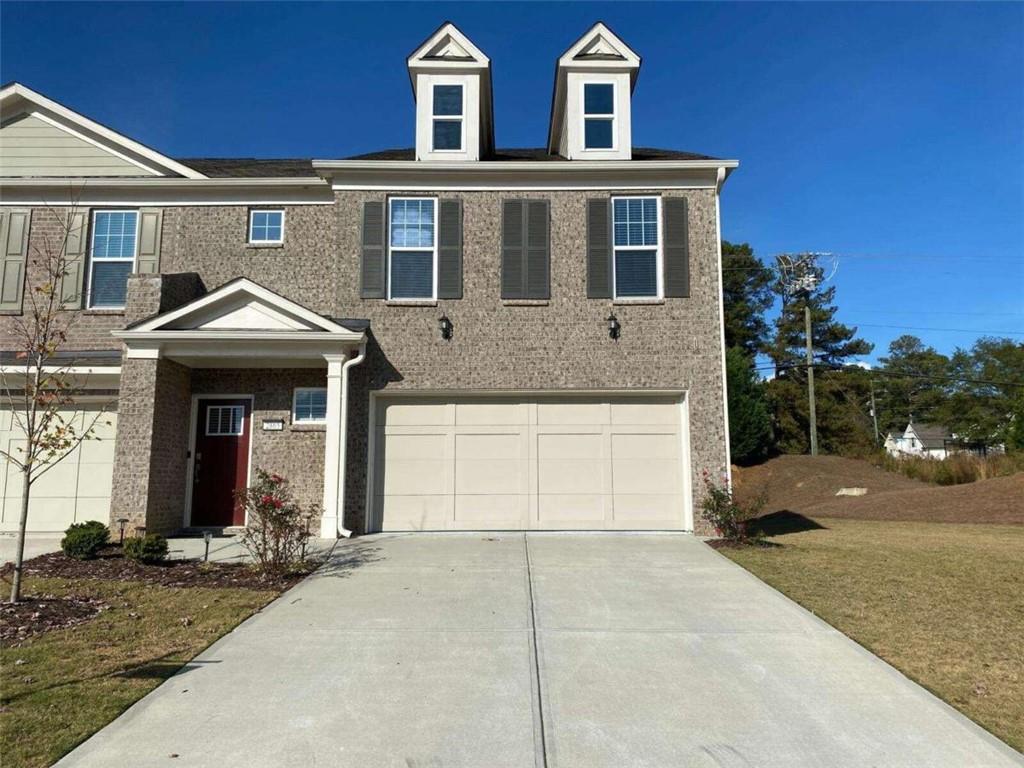 a front view of a house with yard and parking