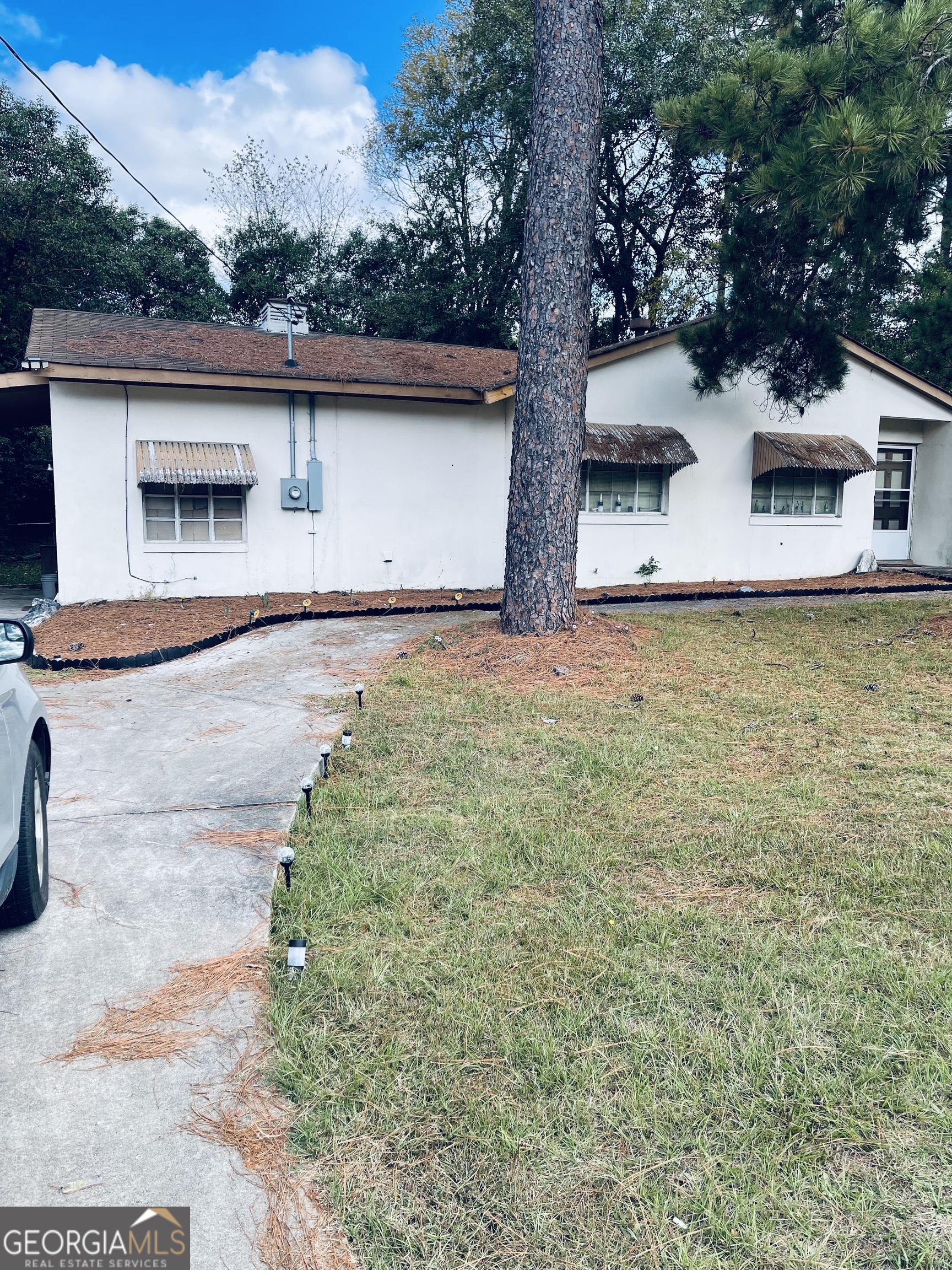 a front view of house with yard space and trees in the background