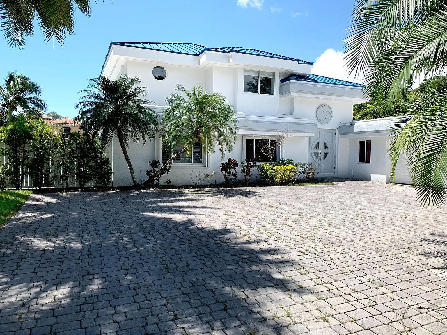 a view of a white house with a yard and palm trees