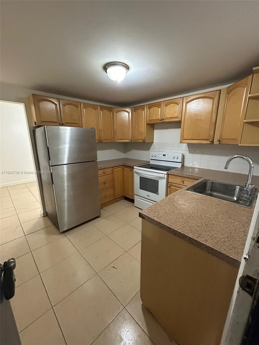 a kitchen with stainless steel appliances granite countertop a sink and a refrigerator