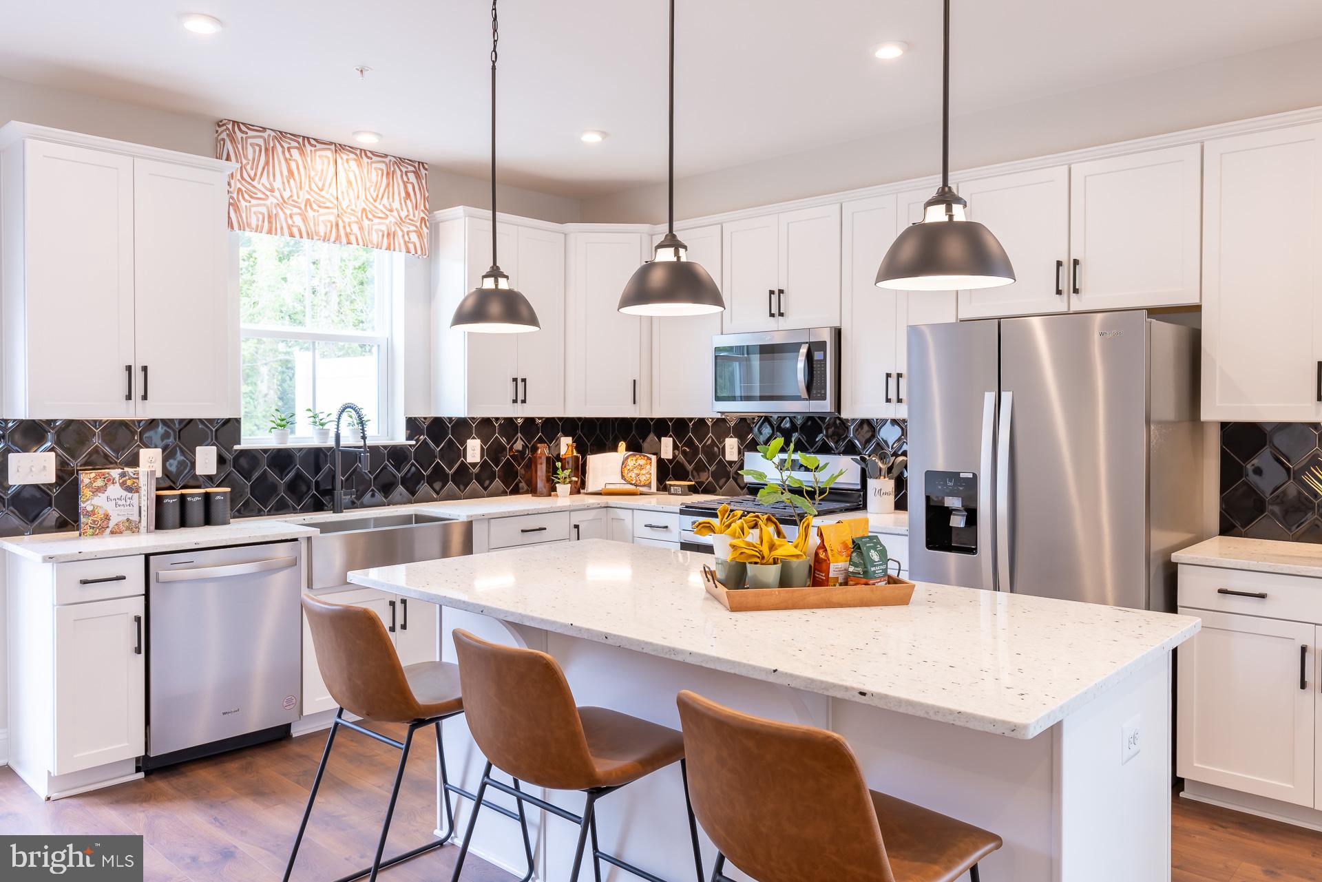 a kitchen with a refrigerator a stove a sink and white cabinets with wooden floor