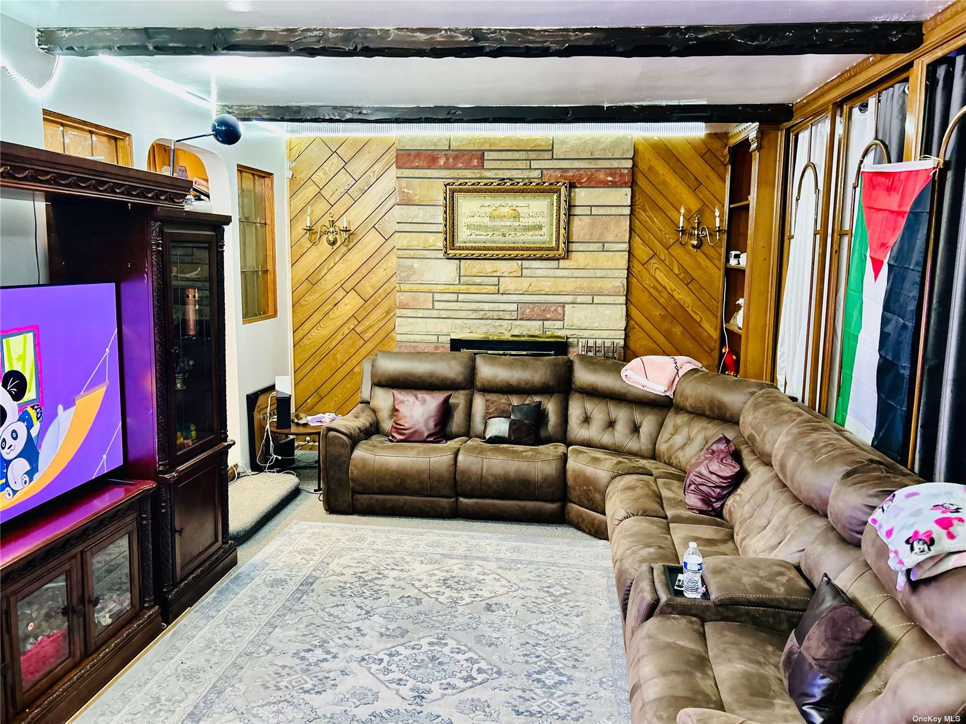 a living room with furniture a flat screen tv and a floor to ceiling window