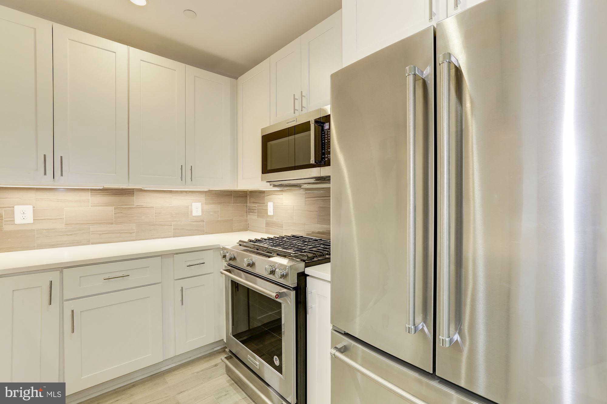 a kitchen with stainless steel appliances granite countertop white cabinets and refrigerator