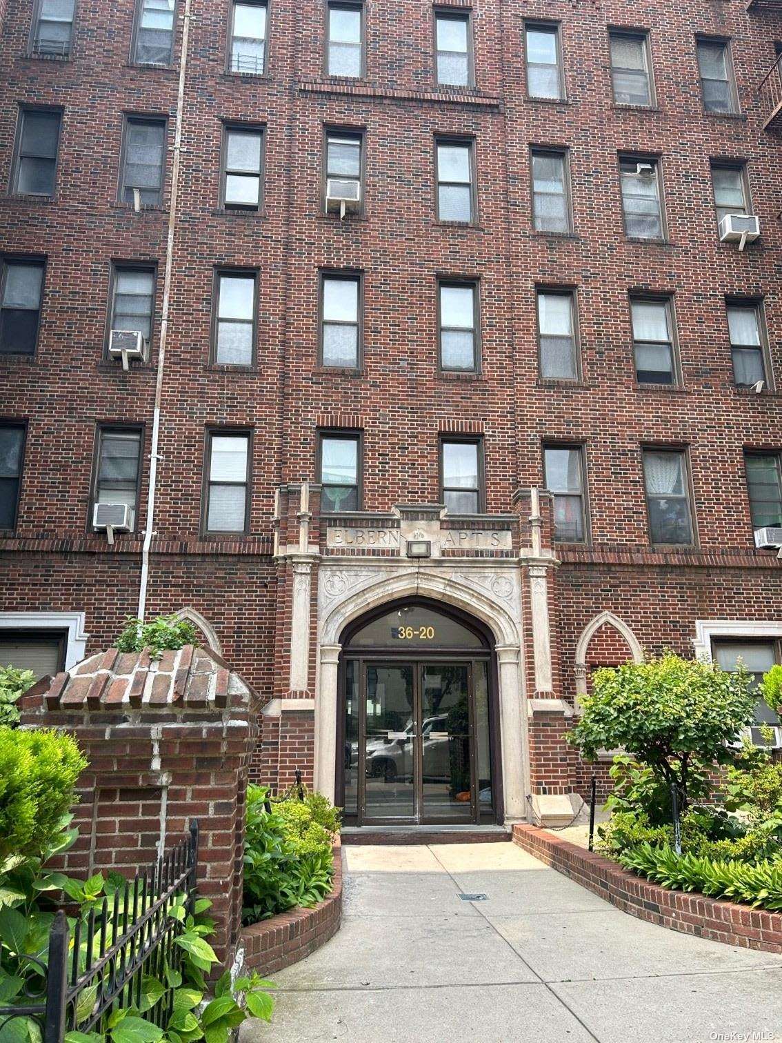 a front view of a building with garden and parking space