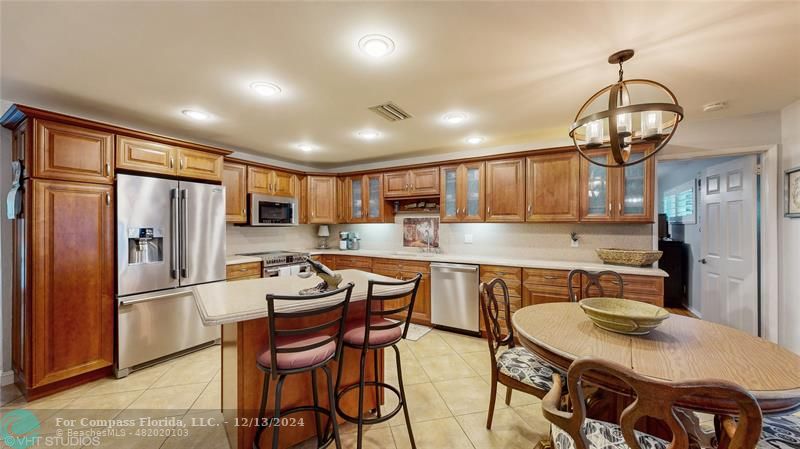 a kitchen with granite countertop a table chairs stove and refrigerator