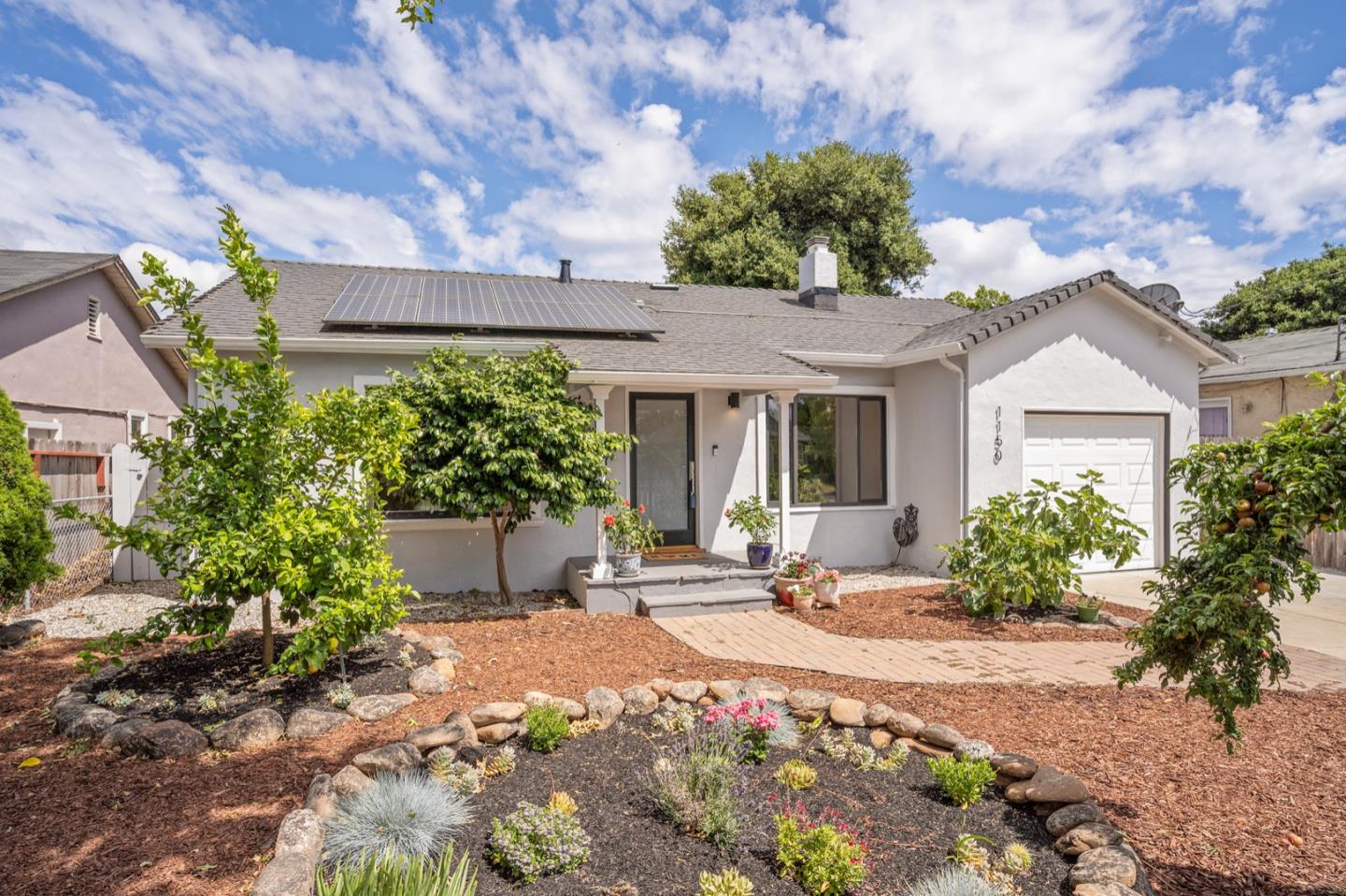 a front view of a house with a yard and potted plants