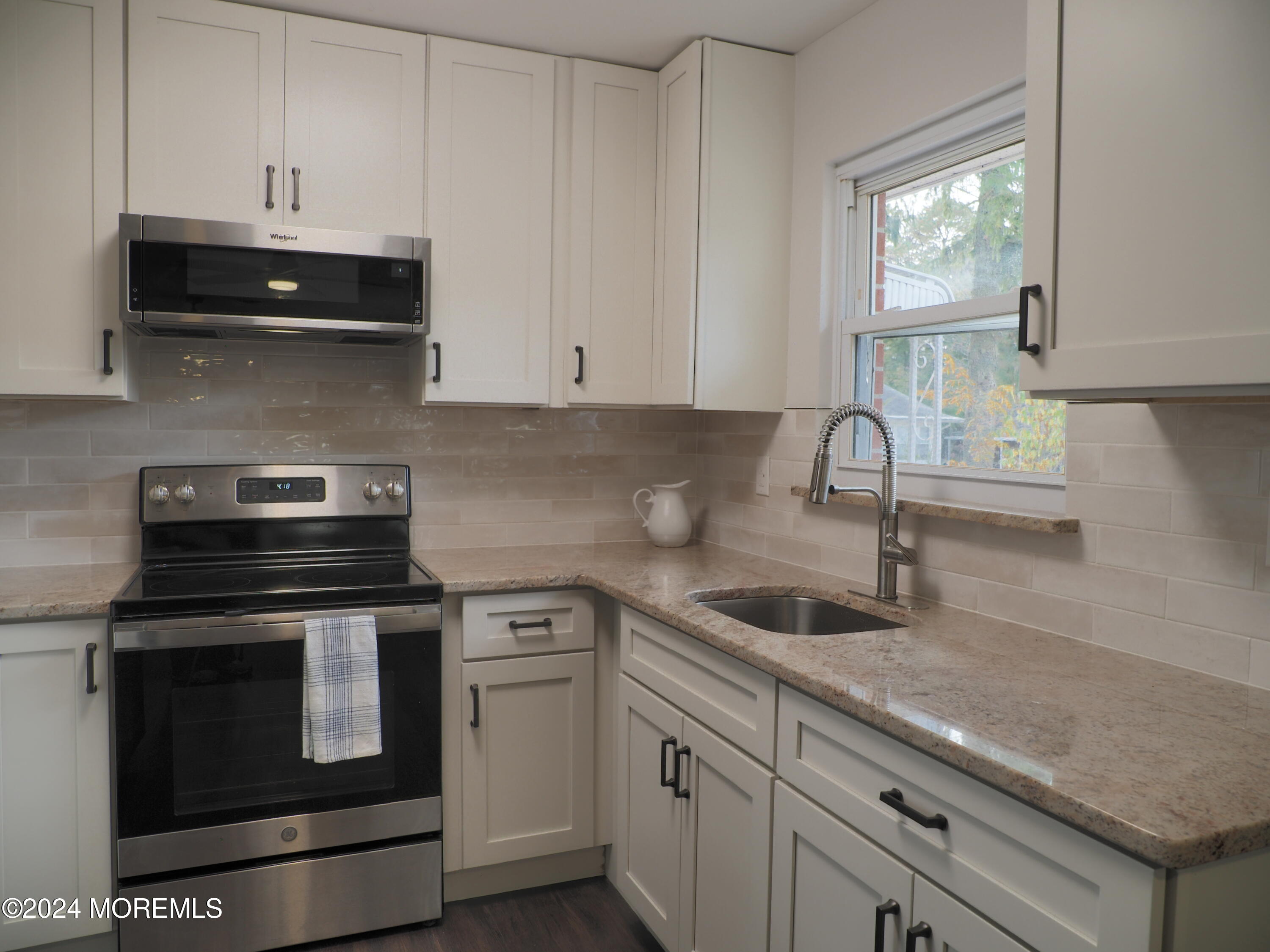 a kitchen with stainless steel appliances granite countertop white cabinets and a stove a sink