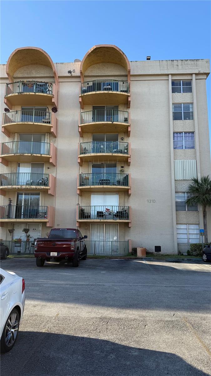 a front view of a building with cars parked