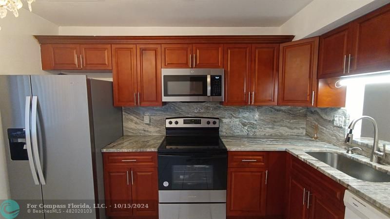 a kitchen with granite countertop wood cabinets and stainless steel appliances