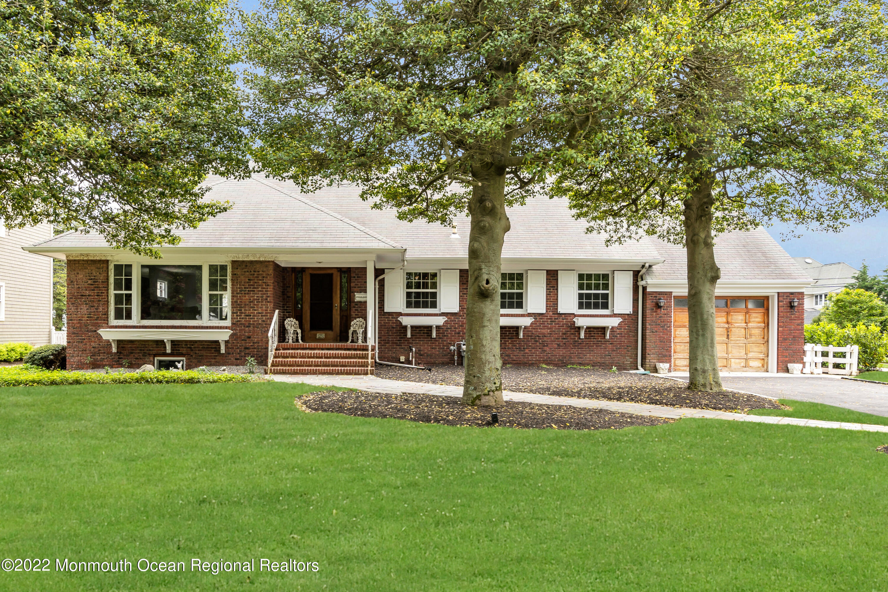 a front view of a house with a garden and trees