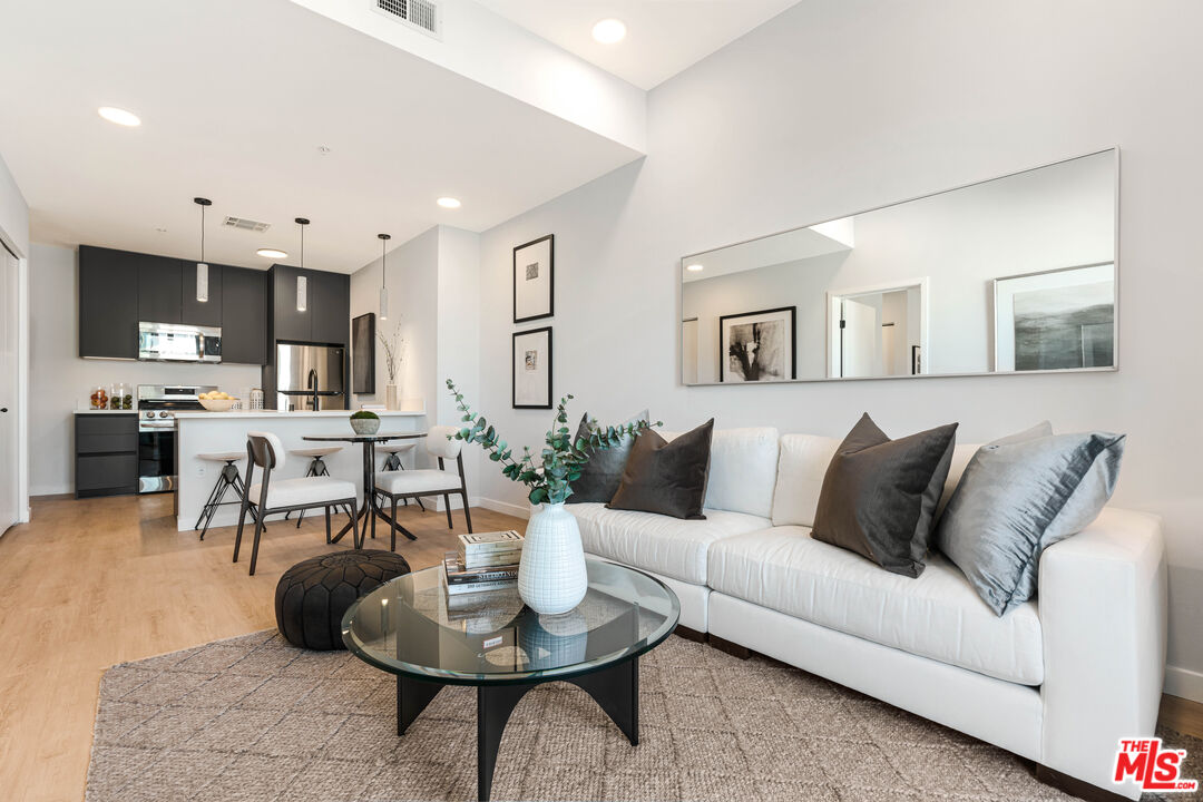 a living room with furniture kitchen and a wooden floor