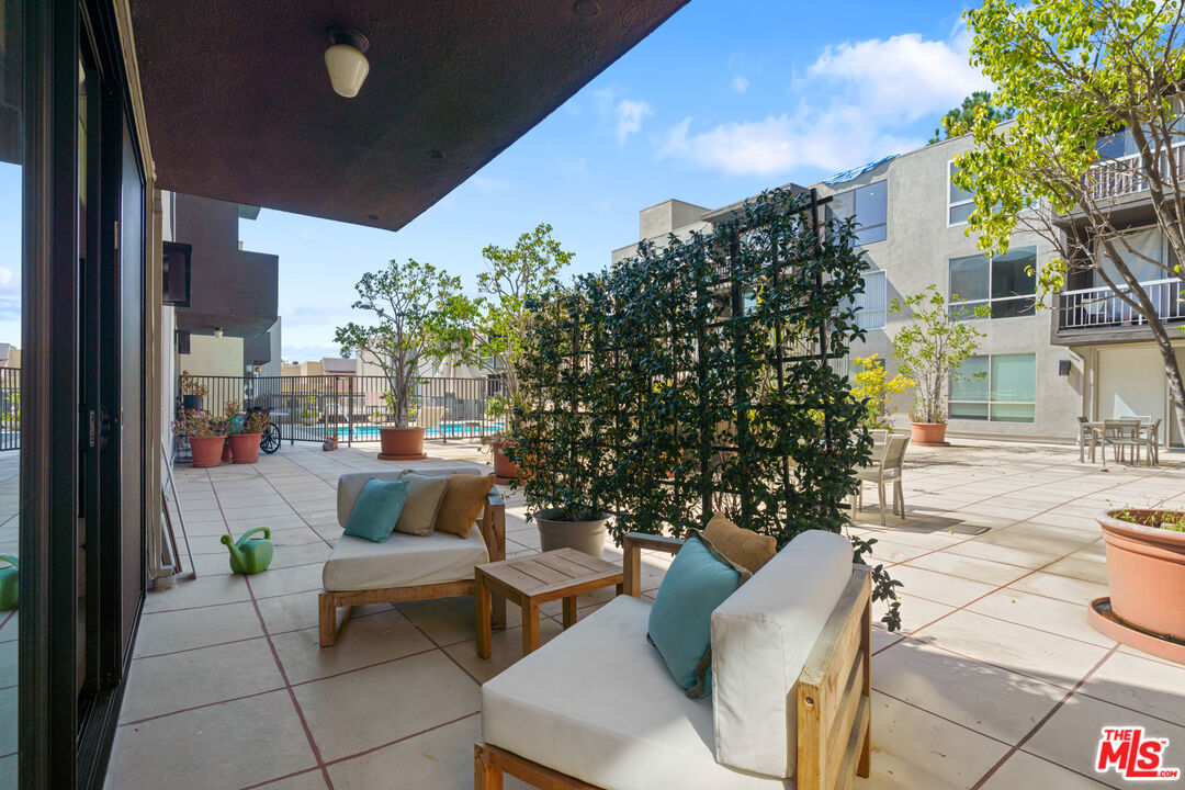 a view of a patio with couches and table and chairs and potted plants