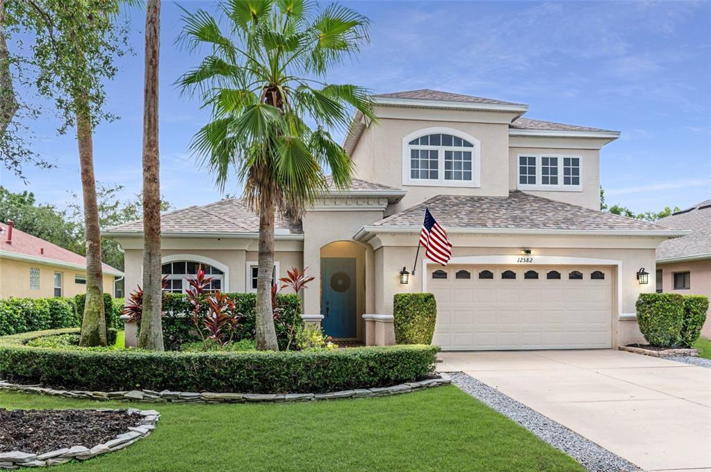 a front view of a house with a garden and palm trees