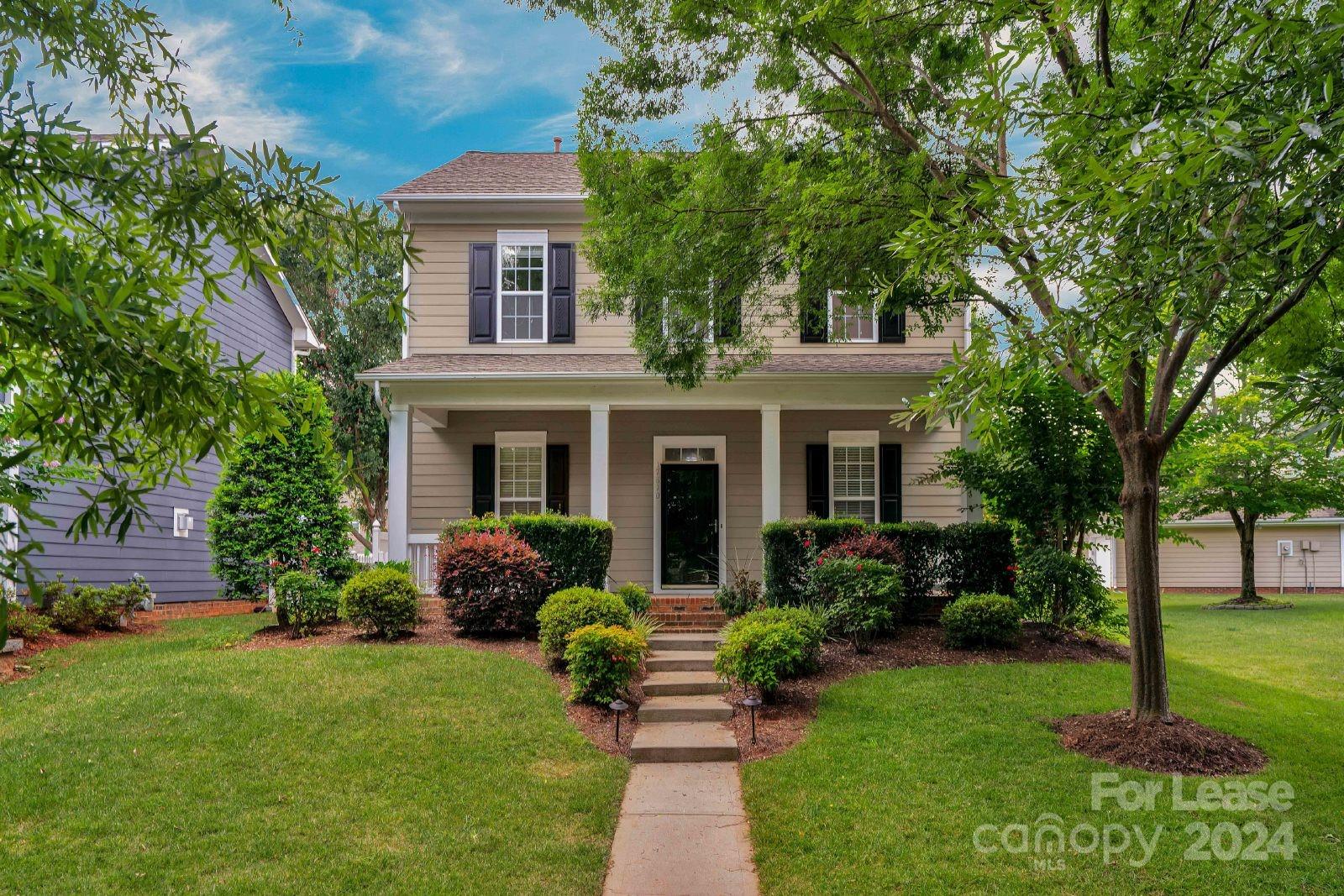 a front view of a house with a garden and trees