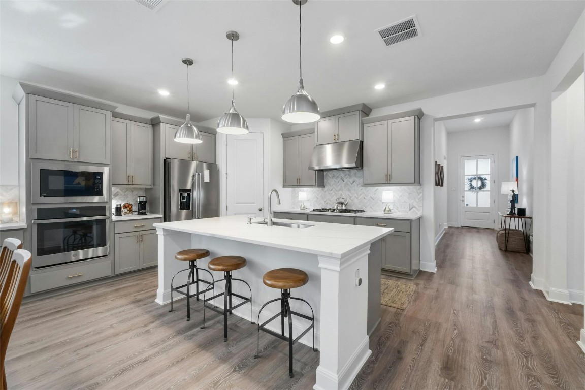 a large kitchen with kitchen island a dining table chairs stainless steel appliances and cabinets