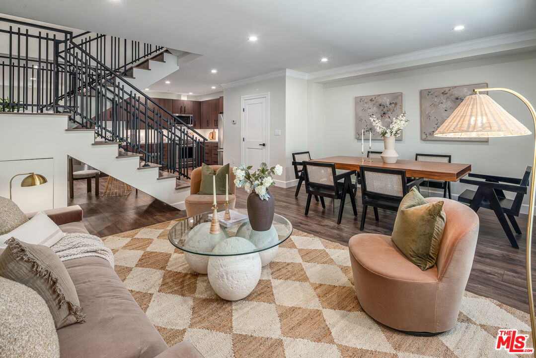 a living room with couches chairs and kitchen view with wooden floor