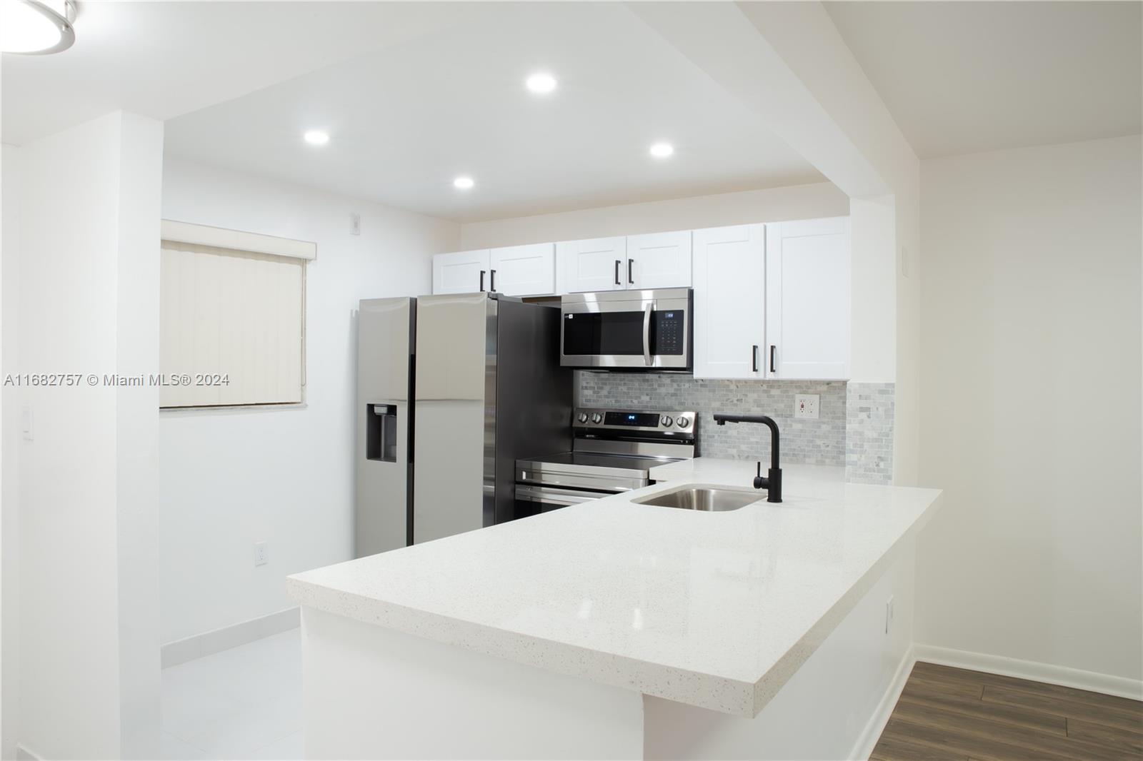 a kitchen with stainless steel appliances a refrigerator sink microwave and cabinets