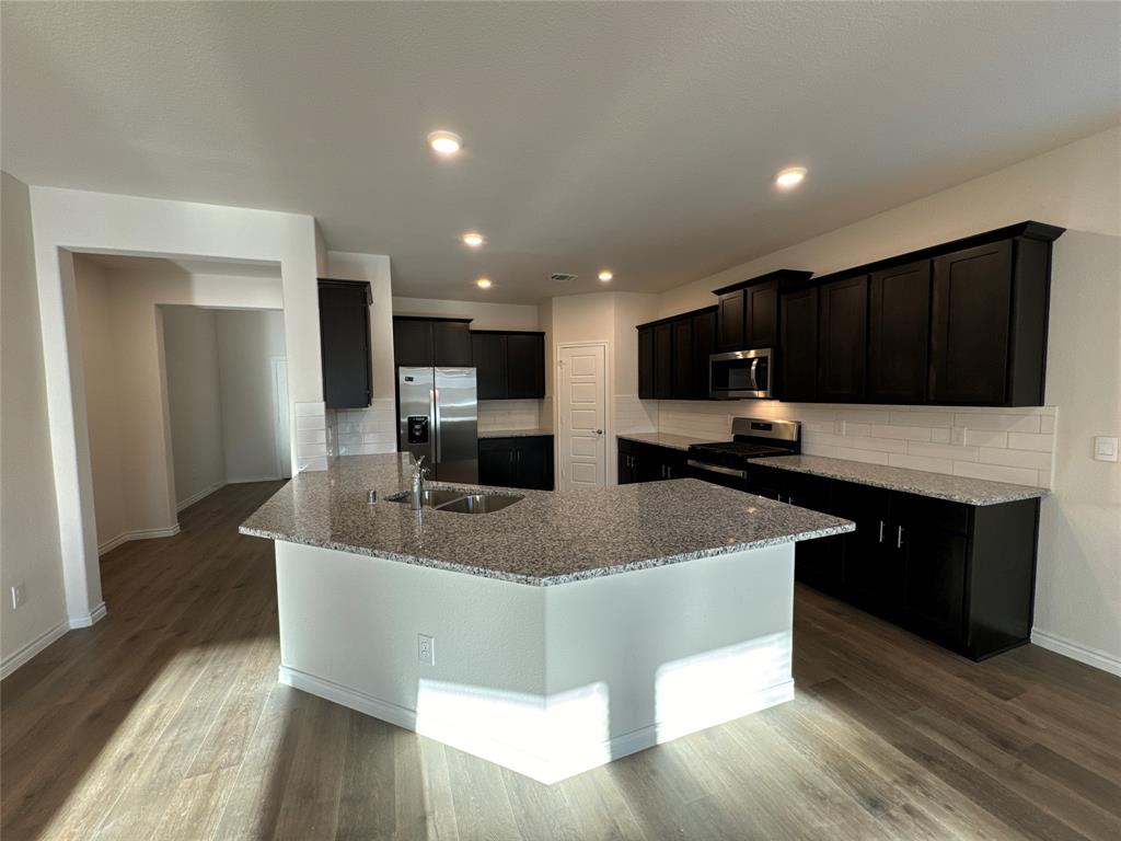 a large kitchen with kitchen island granite countertop a sink and a white appliances