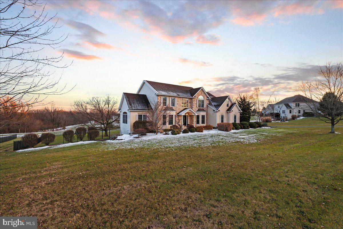 a view of a big house with a big yard and large trees