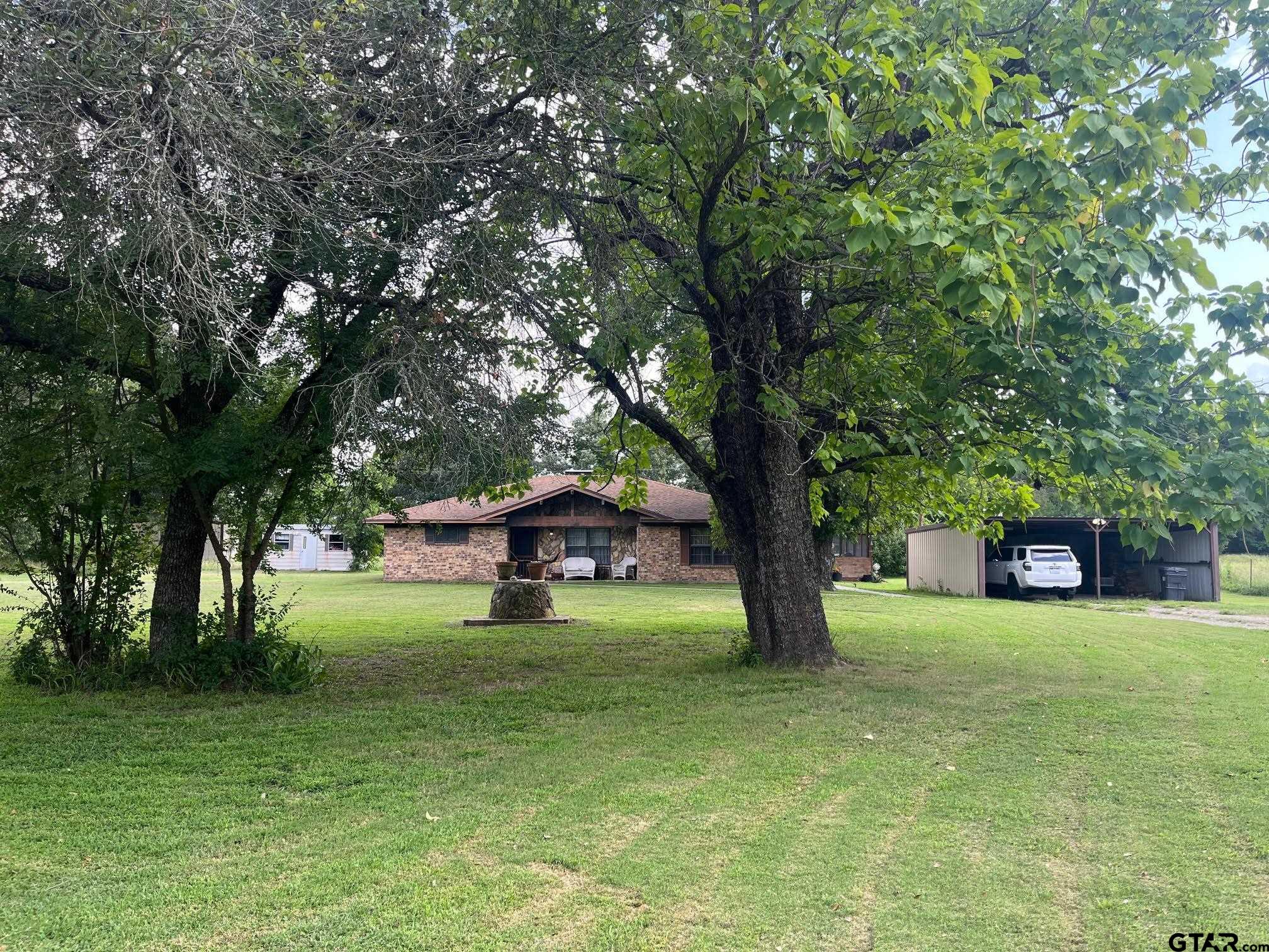 a view of a swimming pool with a big yard and large trees