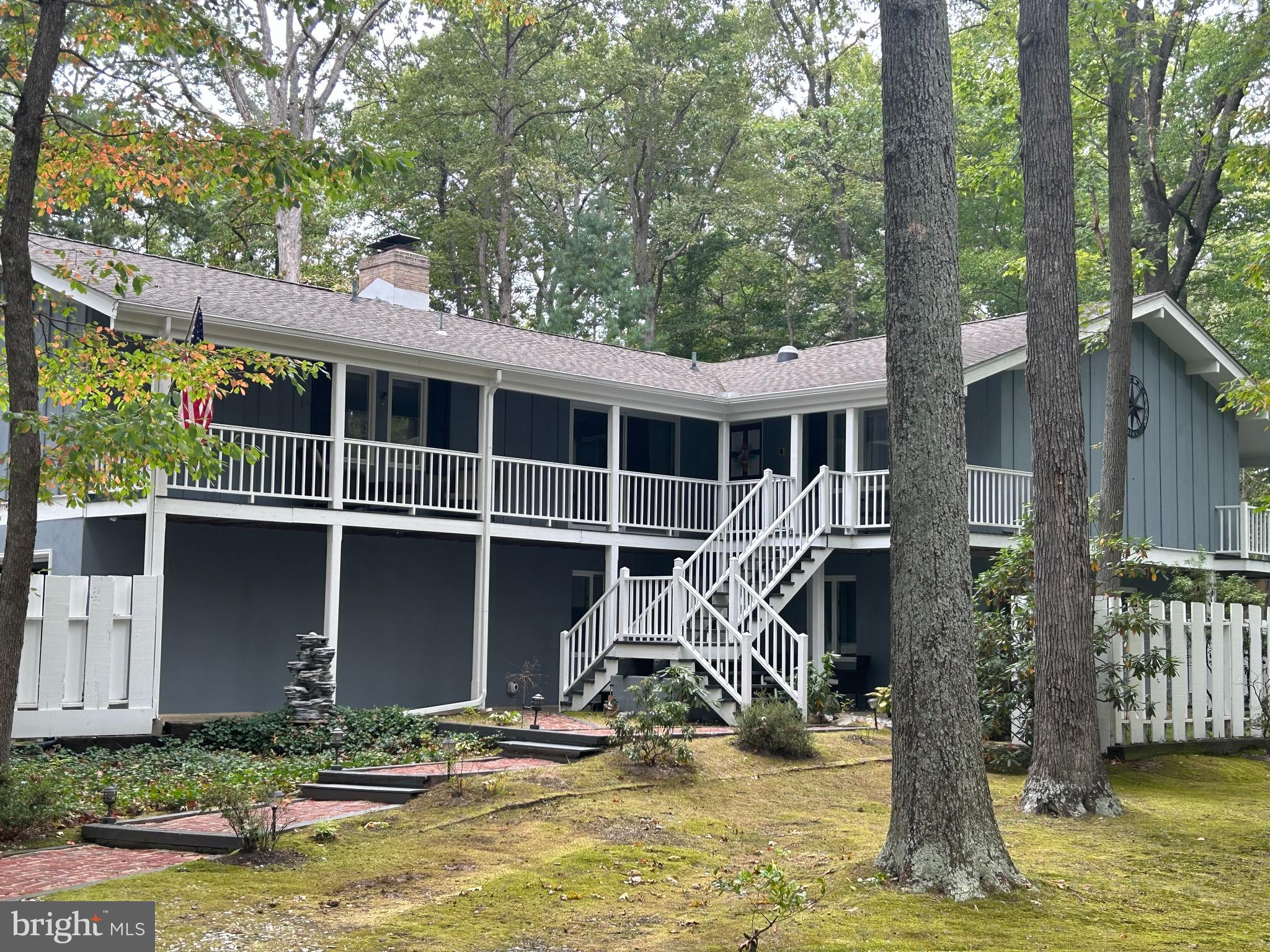 a view of a house with a small yard and large tree and wooden fence