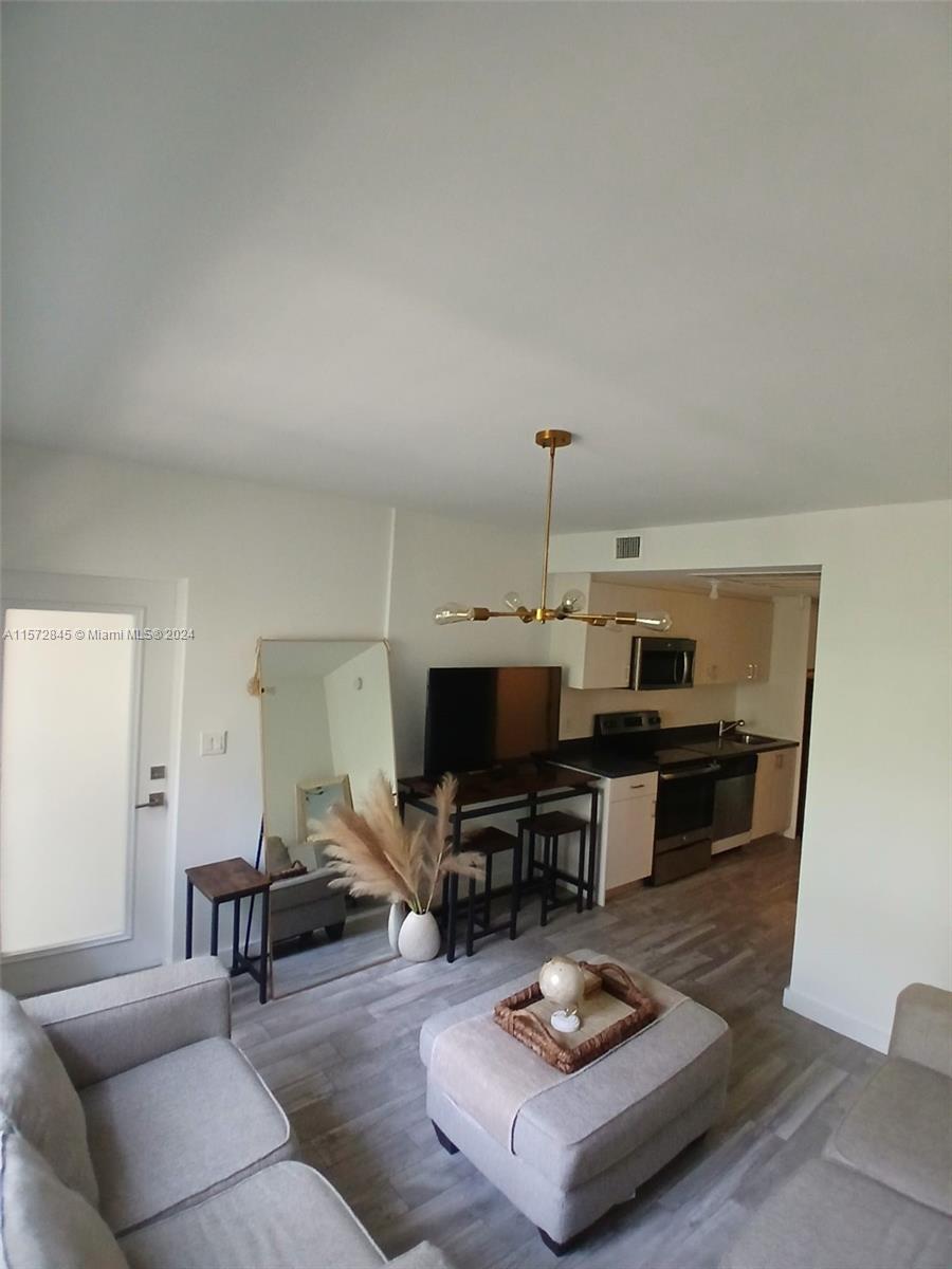 a living room with furniture and a flat screen tv with kitchen view