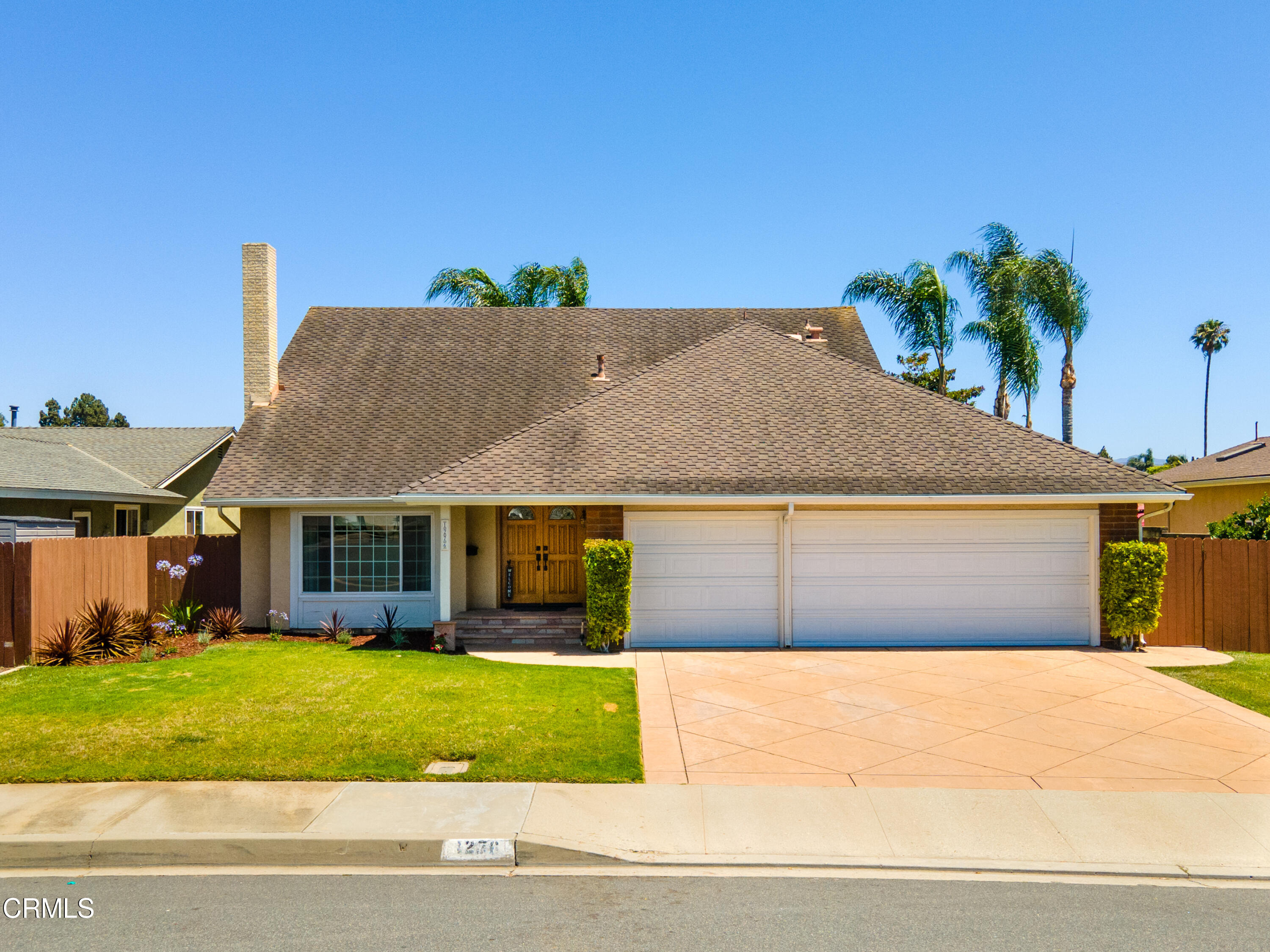 a front view of a house with a yard and potted plants