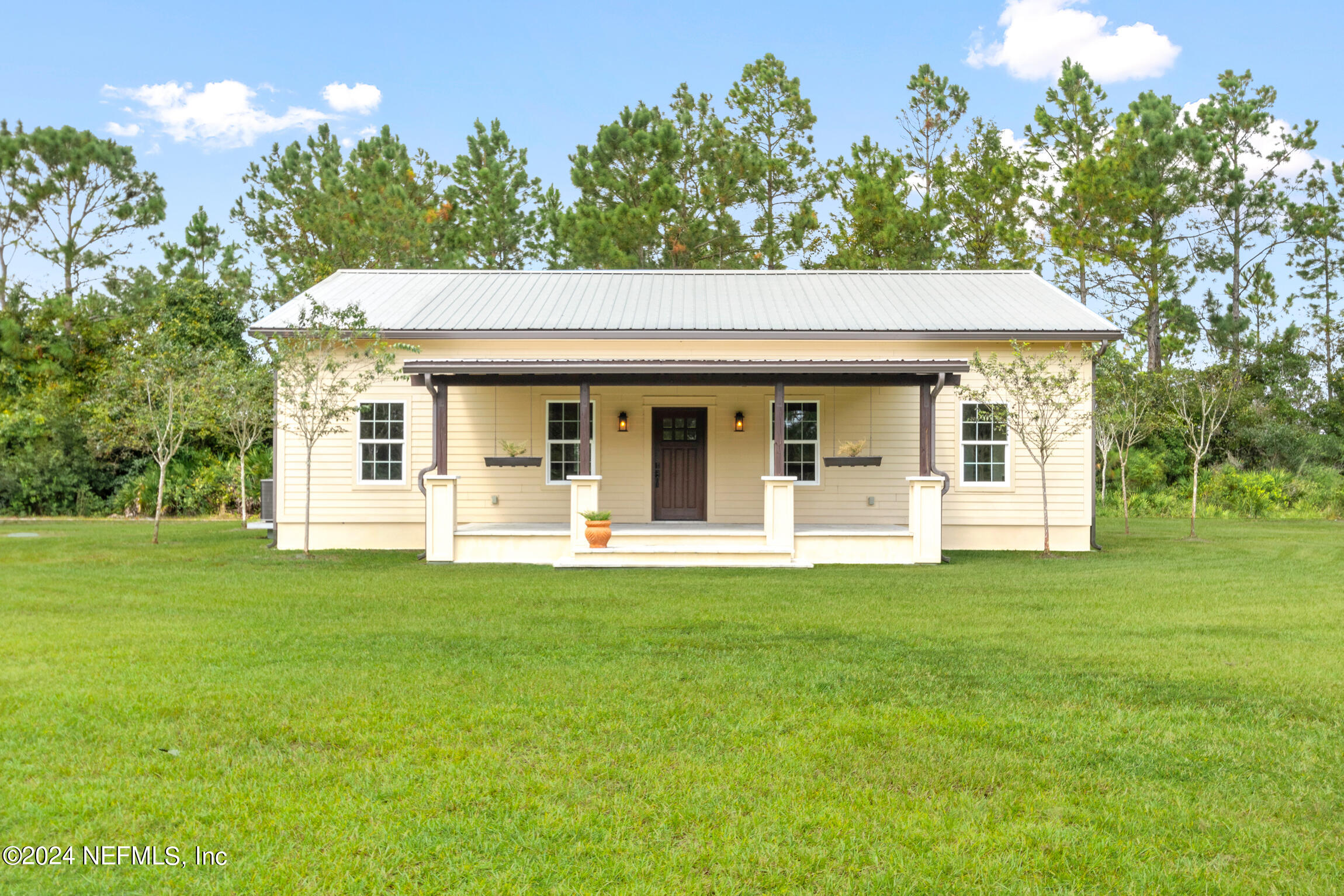 a view of a white house with a big yard and large trees